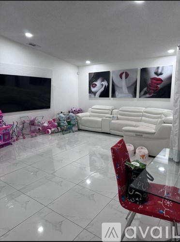 A living room with a white sofa, a red chair, and a television.