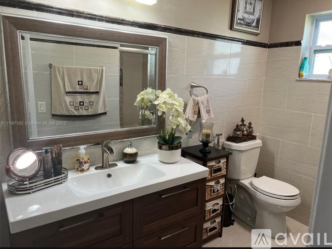 A bathroom with a toilet, sink, and mirror.
