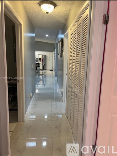 A hallway with a marble floor and a red door on the right.