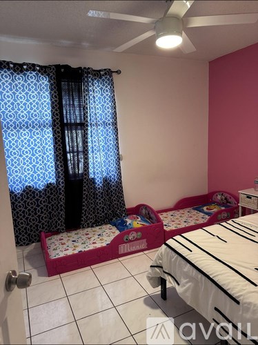 A room with a pink wall and a bed with a white and black striped comforter.