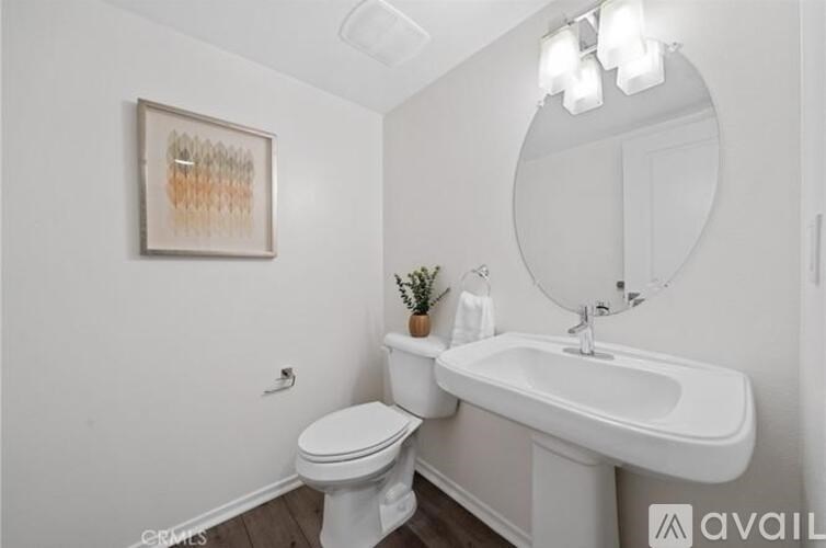 A white bathroom with a toilet, sink, and mirror.