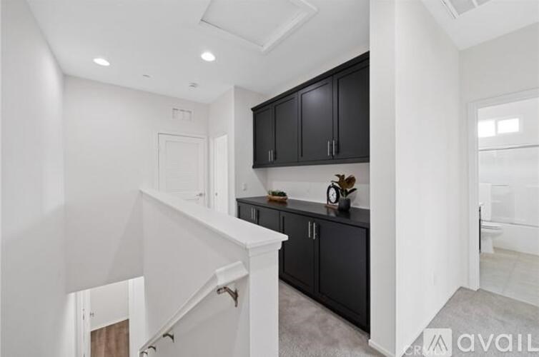 A modern kitchen with black cabinets and a white staircase.