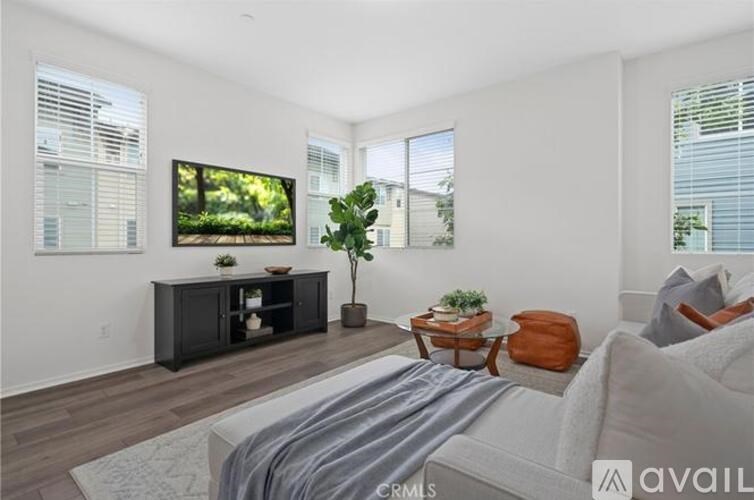 A living room with a grey couch, a black entertainment center, and a flat screen TV mounted on the wall.