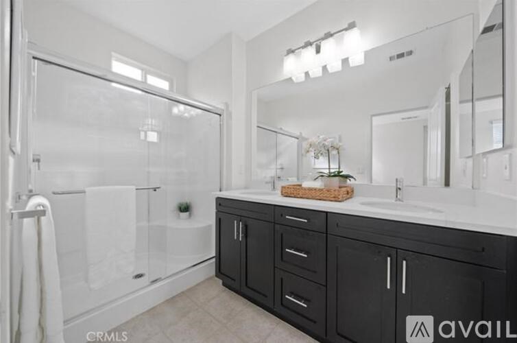 A bathroom with a glass shower stall and a sink with a basket on top of it.