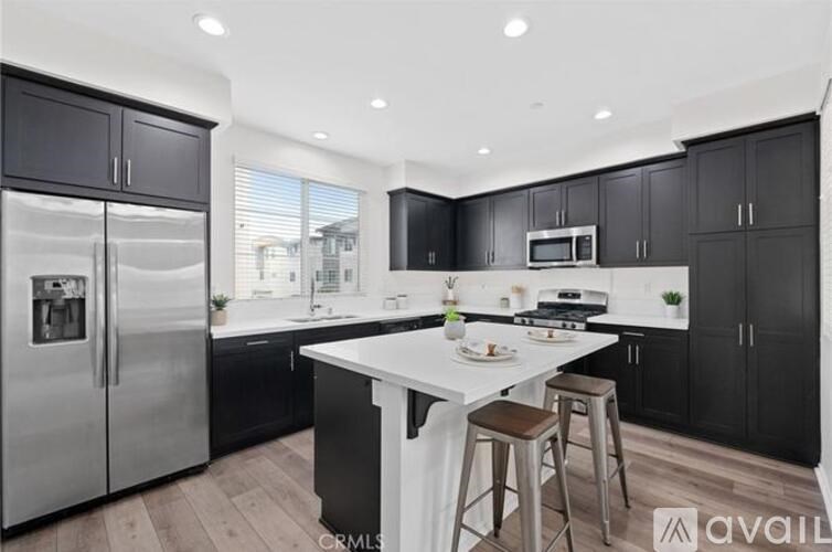 A modern kitchen with black cabinets and a white island.