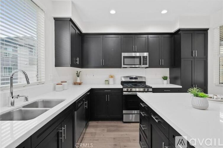 A modern kitchen with black cabinets and stainless steel appliances.