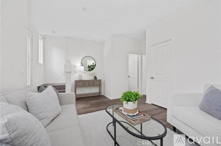 A living room with a white couch and a coffee table with a plant on it.