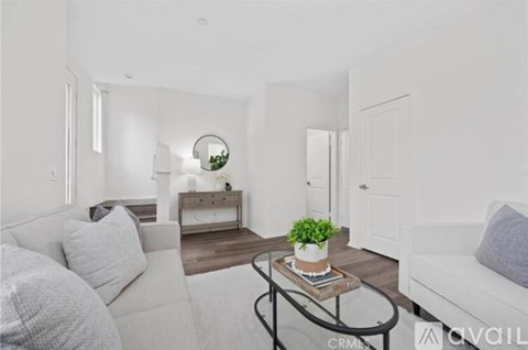 A living room with a white couch and a coffee table with a plant on it.