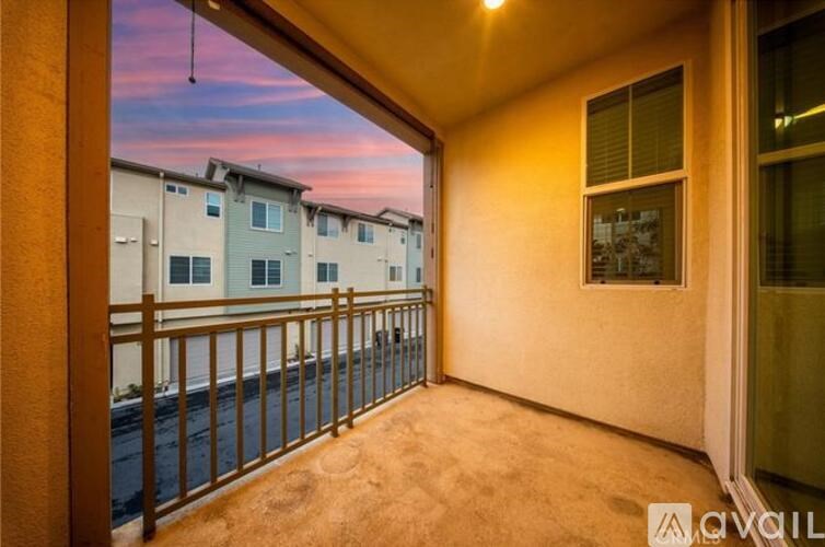 A balcony with a railing and a window overlooking a street.