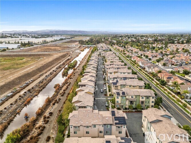 A row of houses with a field and a road in the background.