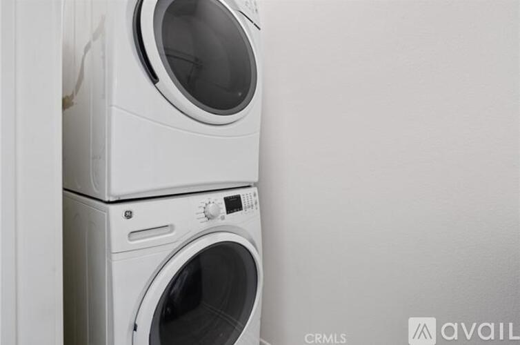 Two white front load washing machines stacked on top of each other.