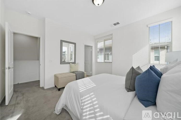 A bedroom with a large bed and a window with blinds.