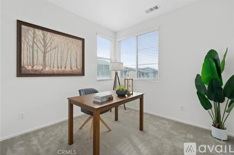 A room with a wooden table, a chair, a painting, and a potted plant.