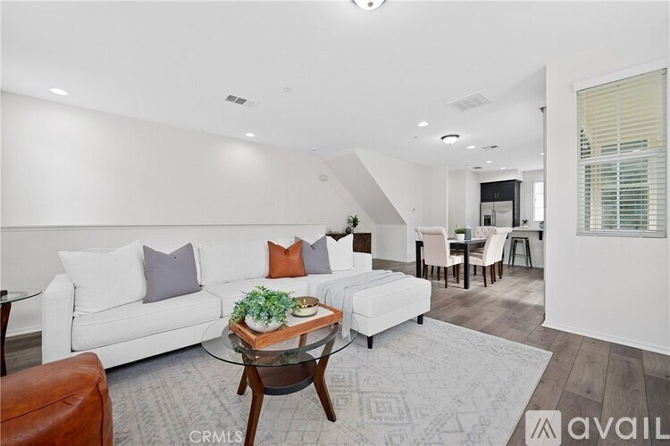 A living room with a white couch, a glass coffee table, and a rug.