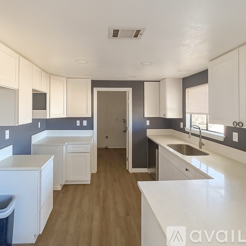 A kitchen with white cabinets and a wooden floor.