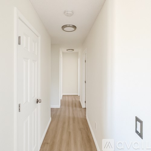 A long hallway with white walls and a carpeted floor.
