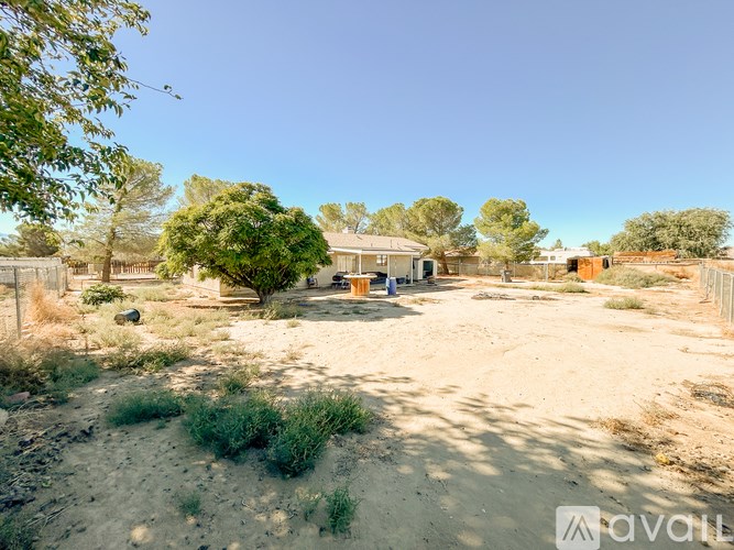 A dirt area with a house and trees in the background.