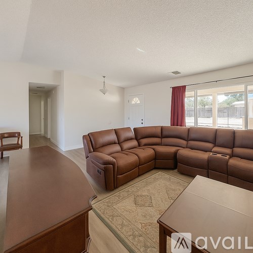 A brown leather sectional sofa in a living room with a wooden table and a rug.