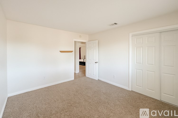 A carpeted room with a door on the right and a hallway leading to another room.