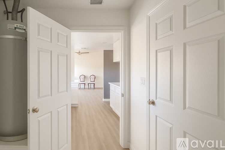 A hallway with white doors and a grey refrigerator.