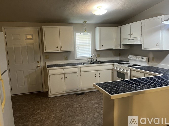 A kitchen with white cabinets and a black countertop.