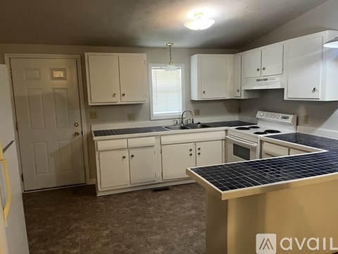 A kitchen with white cabinets and a black countertop.