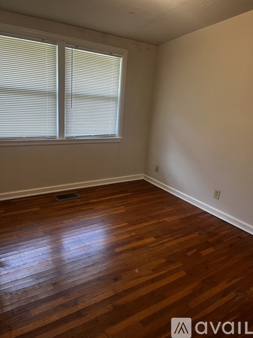 A room with wooden floors and a window with blinds.
