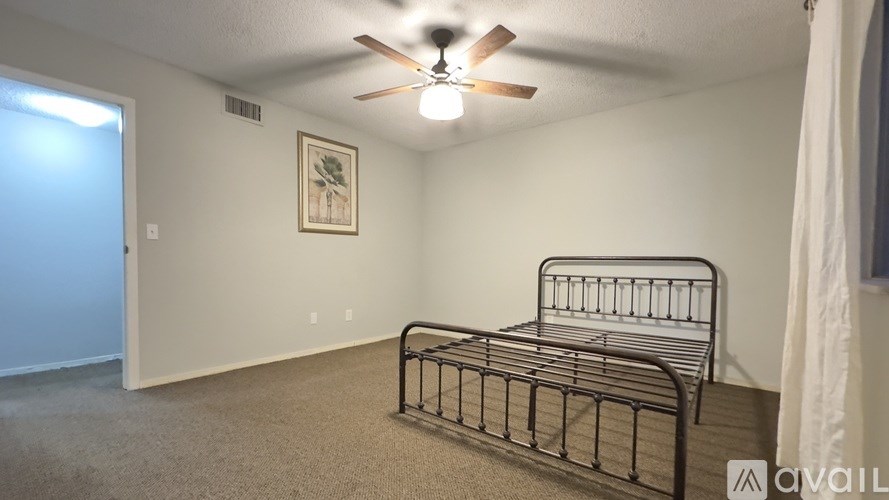 A bedroom with a bed, ceiling fan, and a picture on the wall.