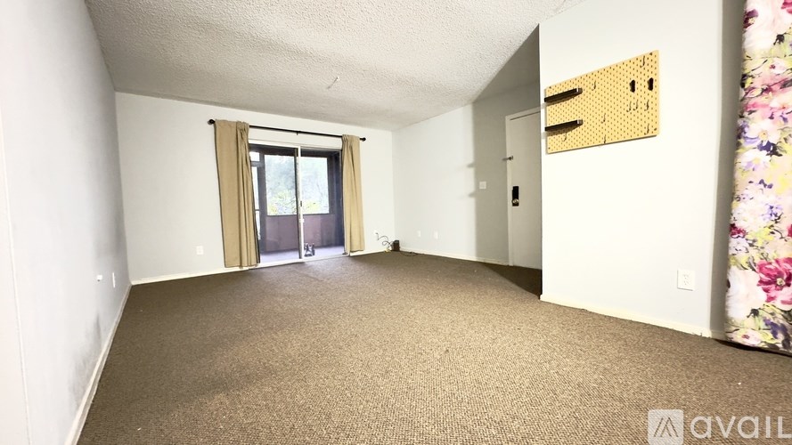 A carpeted room with a door and a window.