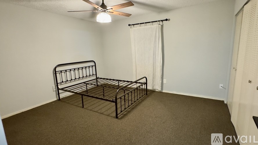 A bedroom with a bed, carpet, and a ceiling fan.