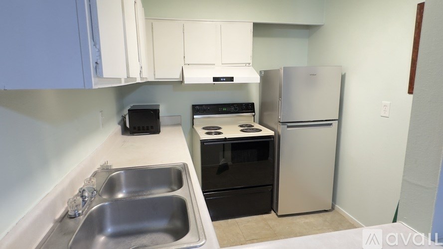 A kitchen with a sink, stove, and refrigerator.