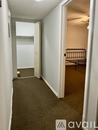 A carpeted hallway with a bedroom at the end.