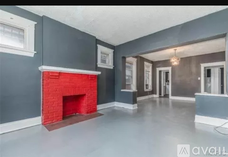 A room with a red fireplace and grey walls.