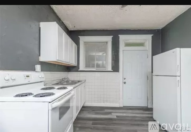 A kitchen with white appliances and a white door.