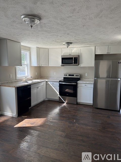 A kitchen with white cabinets and a wooden floor.