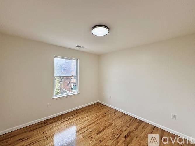 A room with wooden flooring and a window showing an outdoor view.