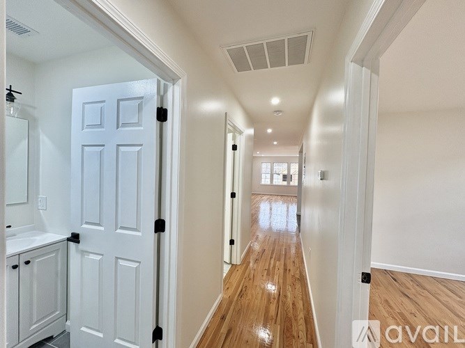 A long hallway with a white door on the left and a white wall on the right.