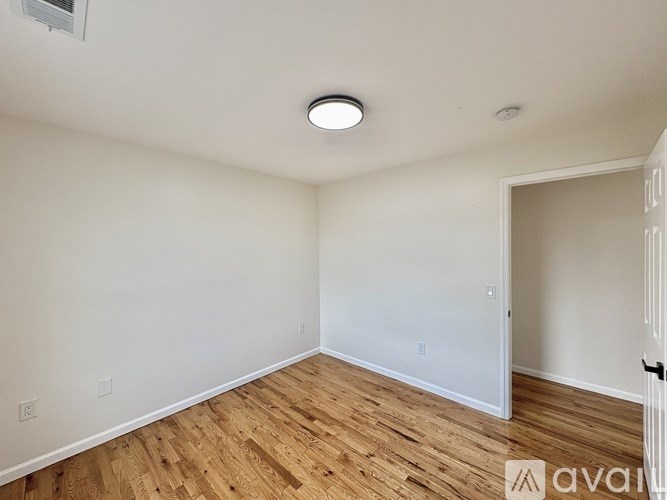 A room with wooden flooring and white walls.