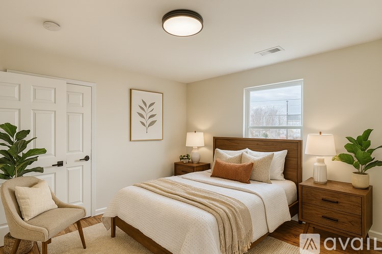 A well-lit bedroom with a large bed, a chair, and a plant.