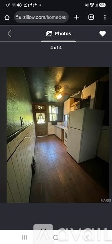 A long, narrow hallway with white cabinets on the left and a window in the distance.