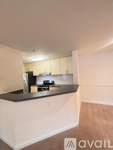 A kitchen with white walls and a black countertop.