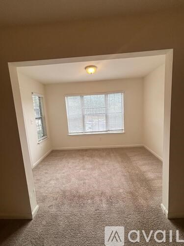 A room with a carpeted floor and a window with blinds.