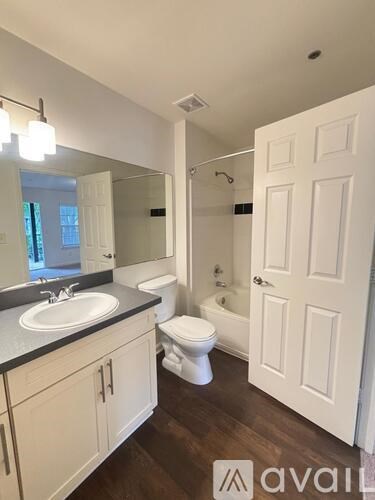 A bathroom with a toilet, sink, and mirror.