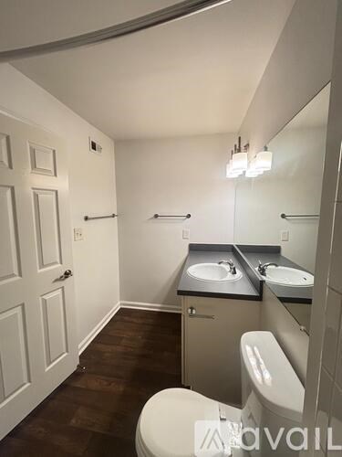 A bathroom with a toilet, sink and mirror.