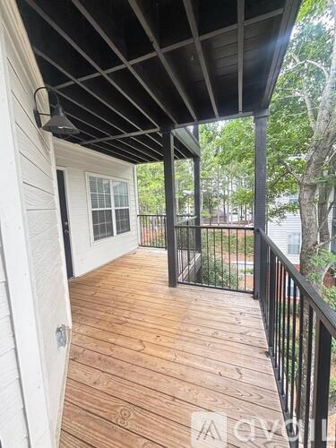 A wooden deck with a black railing and a white house.