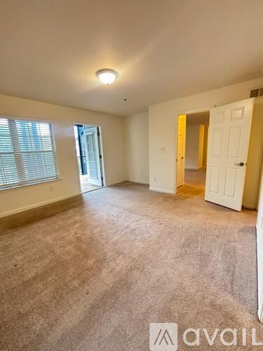 A room with a carpeted floor and a window with blinds.