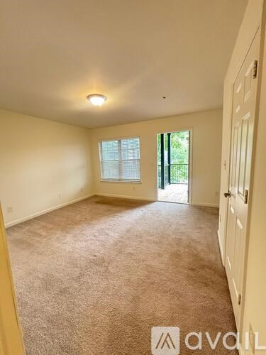 A room with beige carpet and white walls with a window and a door.