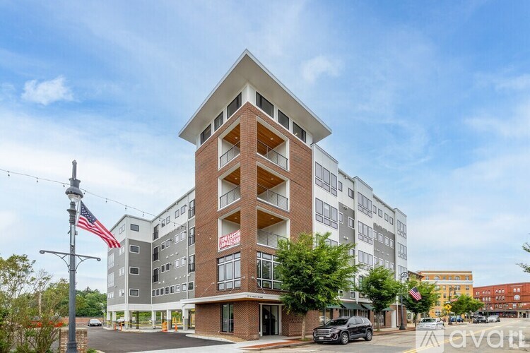 A tall building with a grey and red facade stands in front of a clear blue sky.