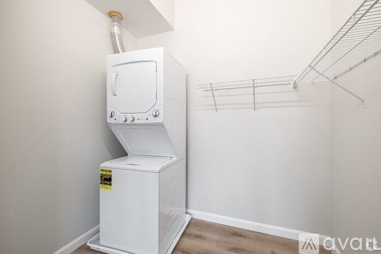 A white industrial-sized oven with a vent on top is in a room with a shelf above it.