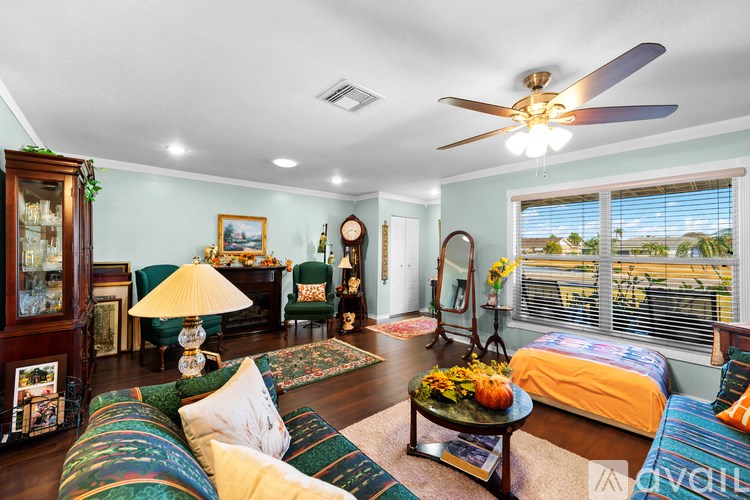 A living room with a ceiling fan and a bed.